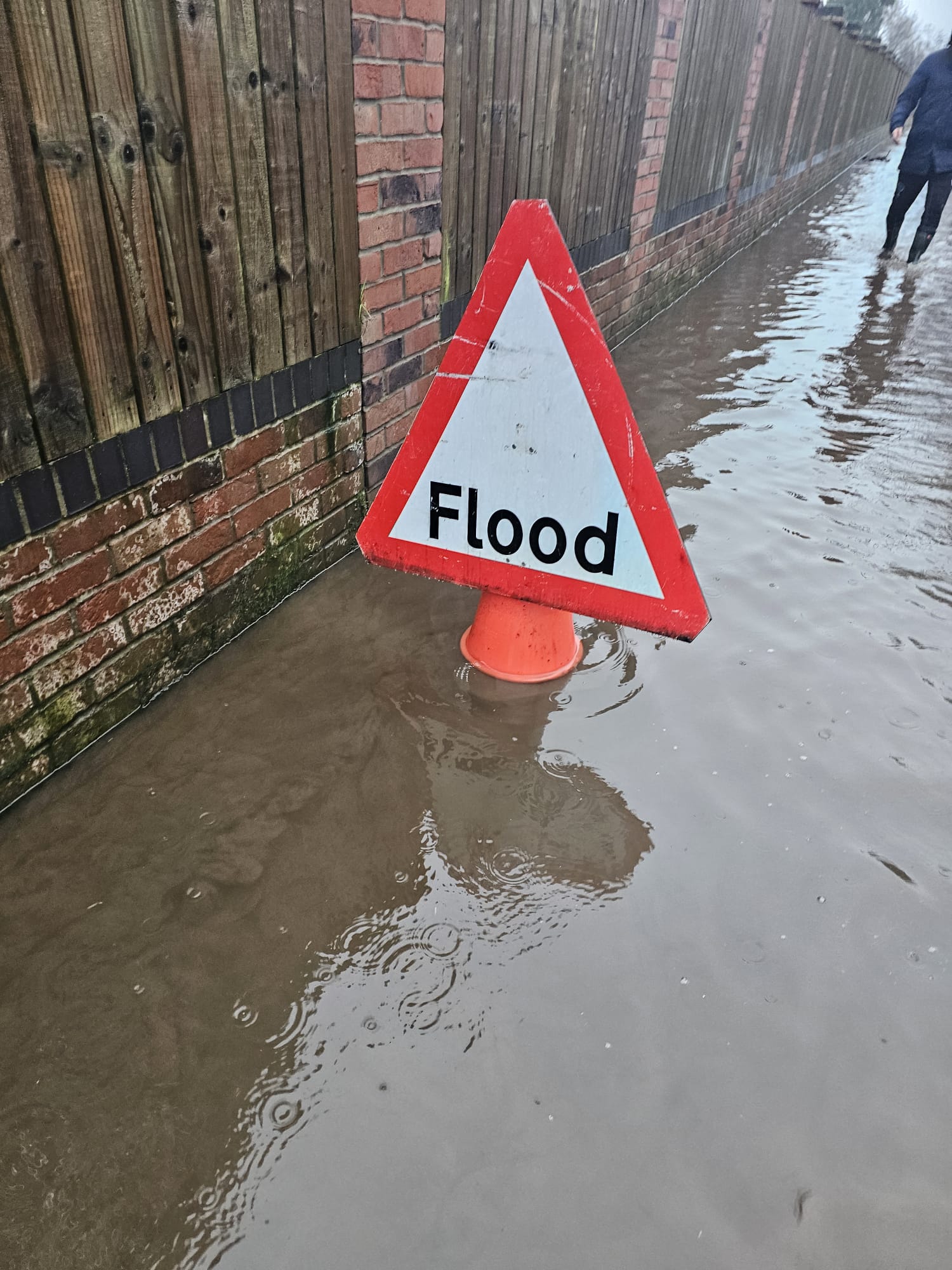 red warning triangle saying flood in a pool of dirty water behind Saxon Avenue